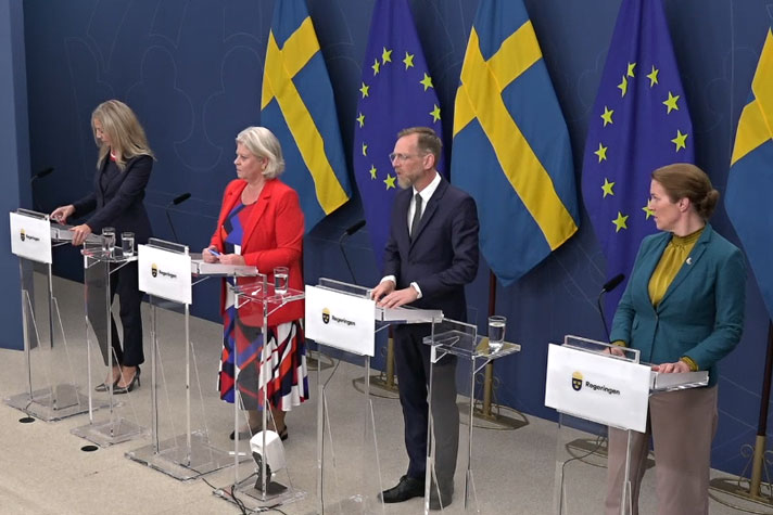 Socialminister Jakob Forssmed, och socialtjänstminister Camilla Waltersson Grönvall, Sverigedemokraternas gruppledare Linda Lindberg och Liberalernas gruppledare Lina Nordquist står vid var sin talarpulpet.